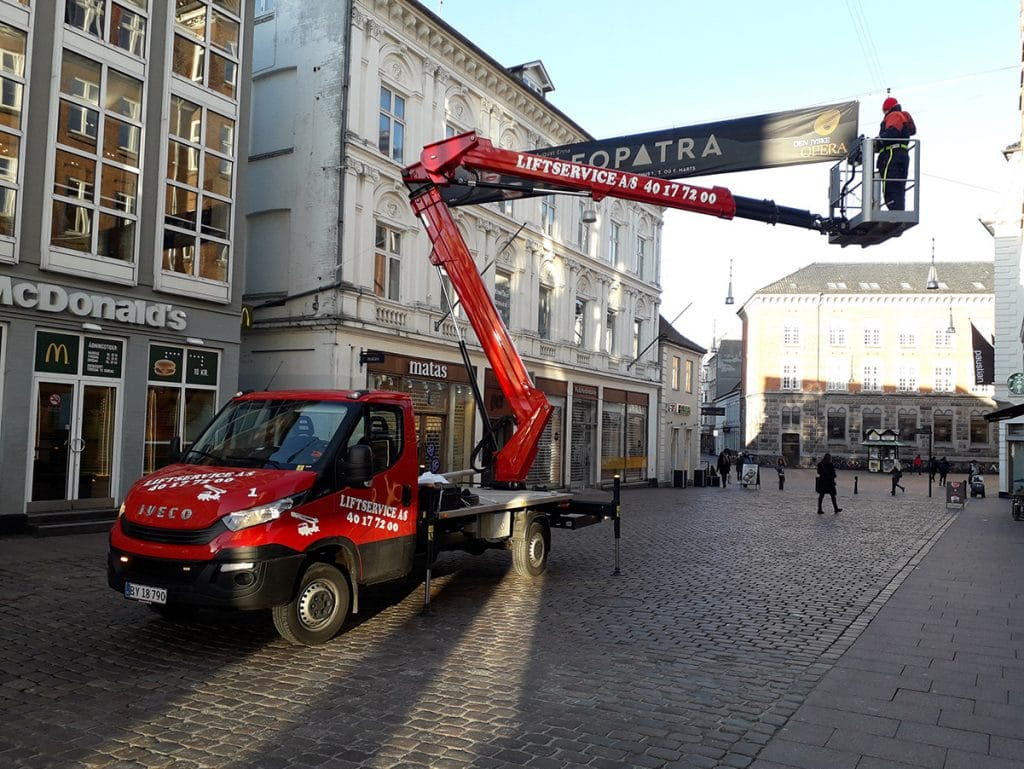 Liftservice monterer banner over gade med lift